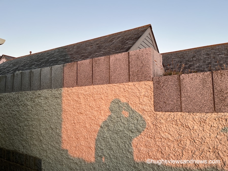 Photo of a shadow on a textured wall that is looking out towards something.