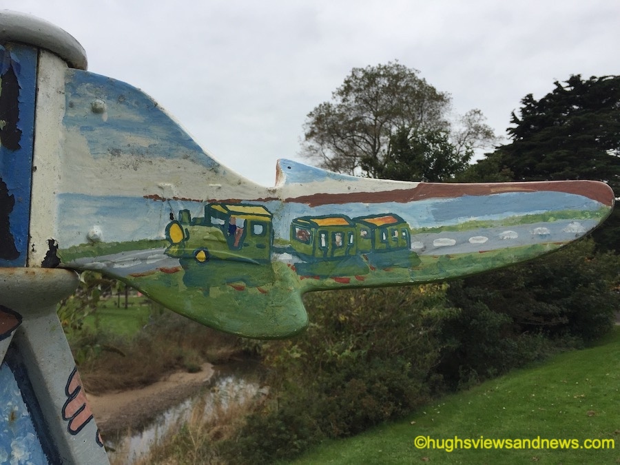 Photo of a sign with a painted image of a land train on it pointing the direction to the land train.