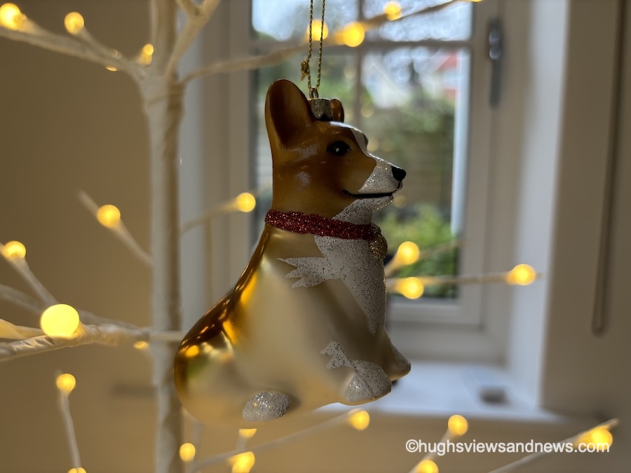 Photo of a Corgi Christmas tree ornament hanging on a white Christmas tree with warm-white lights.