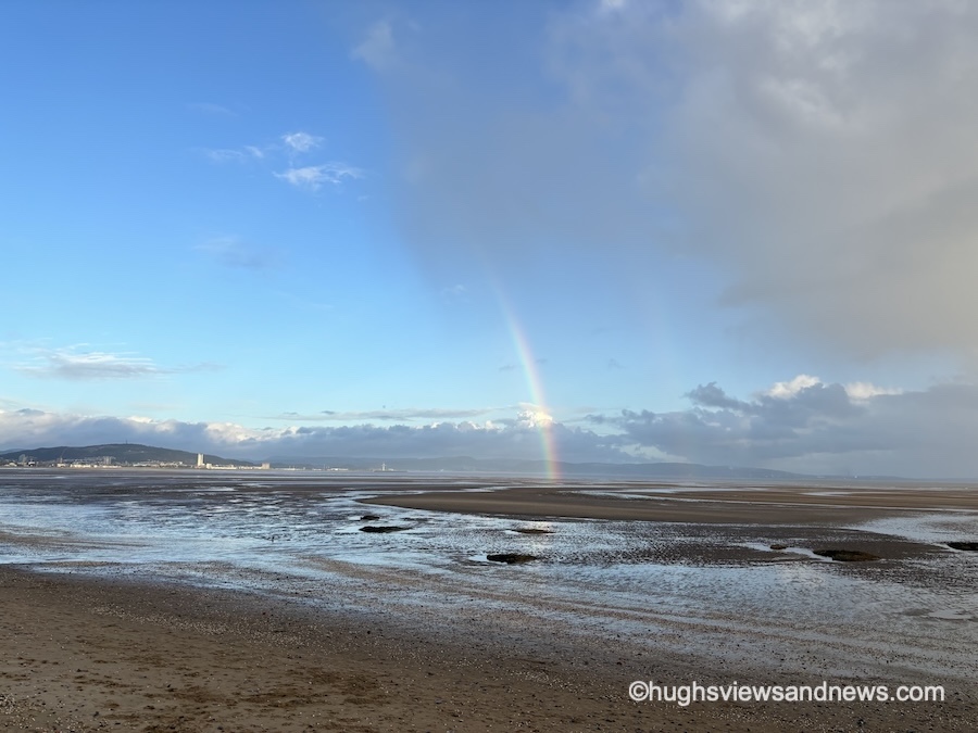 Photo of the beach at Swansea Bay with the city of Swansea in the distance and a double-rainbow over the sea.