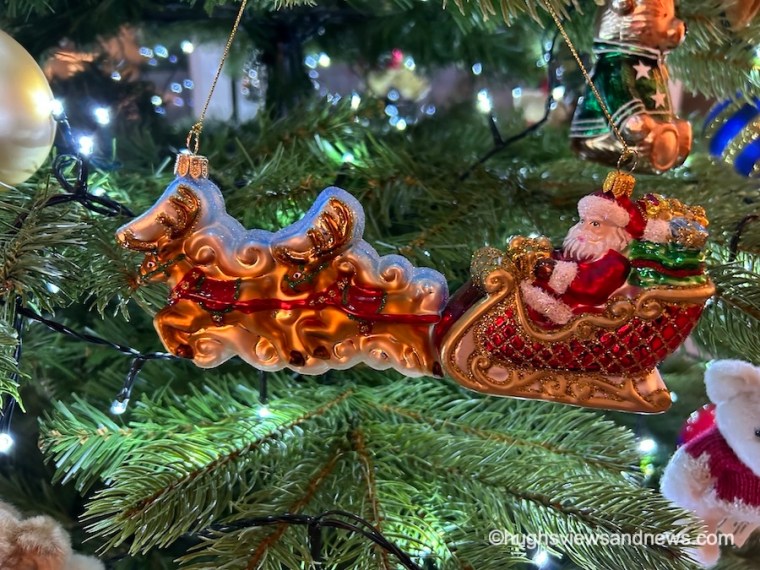 A photo of a Christmas tree ornament of Father Christmas in his sleigh being pulled by reindeer.