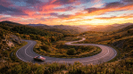 Red convertible car on a winding mountain road at sunset with colorful sky